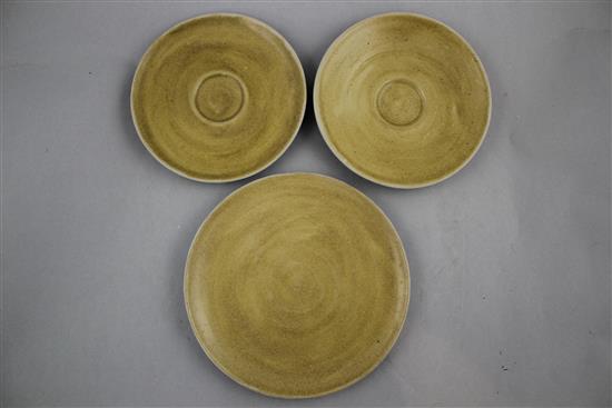 Dame Lucie Rie. A mustard glazed pottery plate and two matching saucers, 18.2cm and 15.2cm